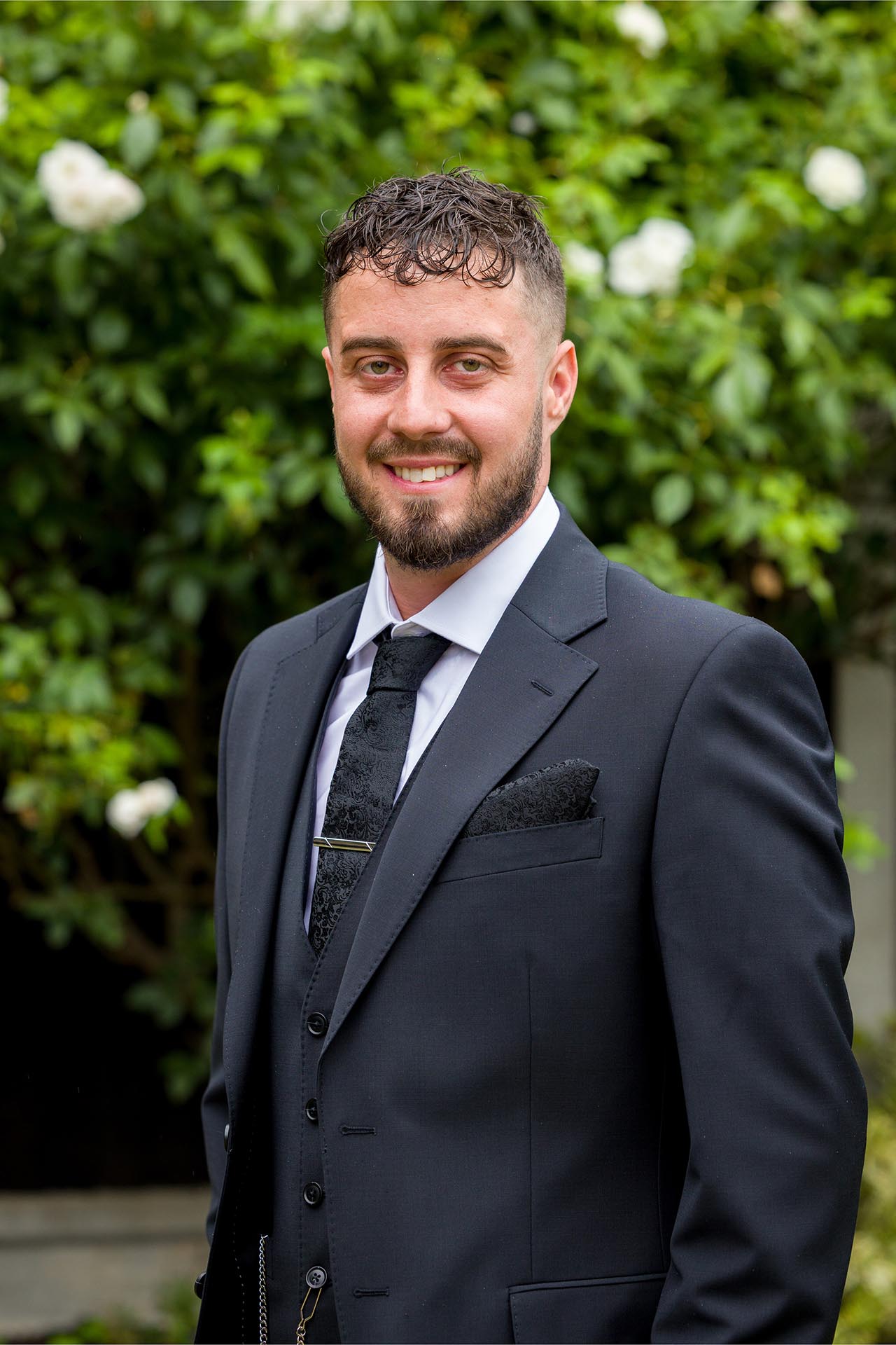 Portrait photograph of groom in garden