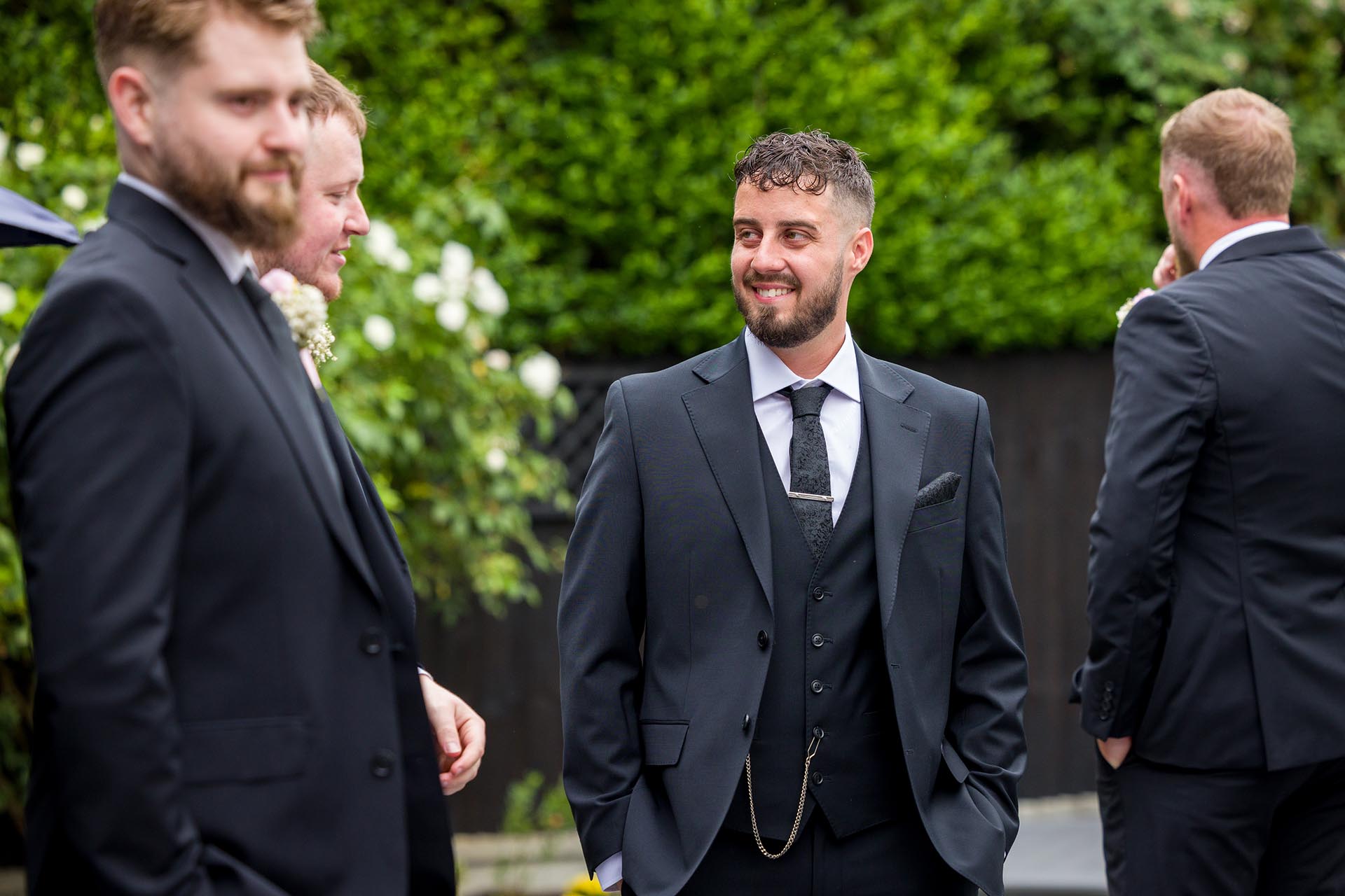 Photograph of groom and his groomsmen chatting before wedding ceremony