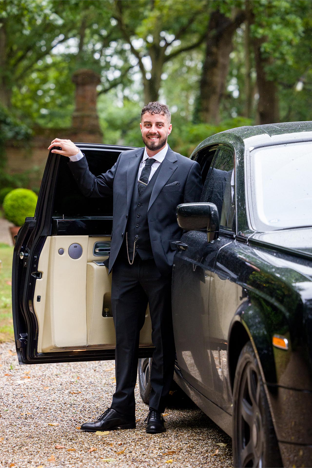Photograph of groom holding the door of a black Rolls-Royce wedding car at Creeksea Place, Burnham-on-Crouch, Essex