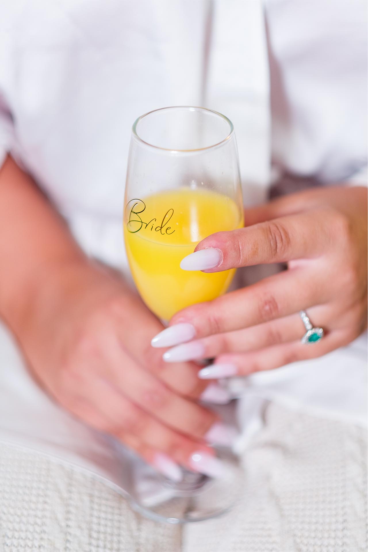 Close-up photograph of bride's hands holding champagne flute containing bucks-fizz