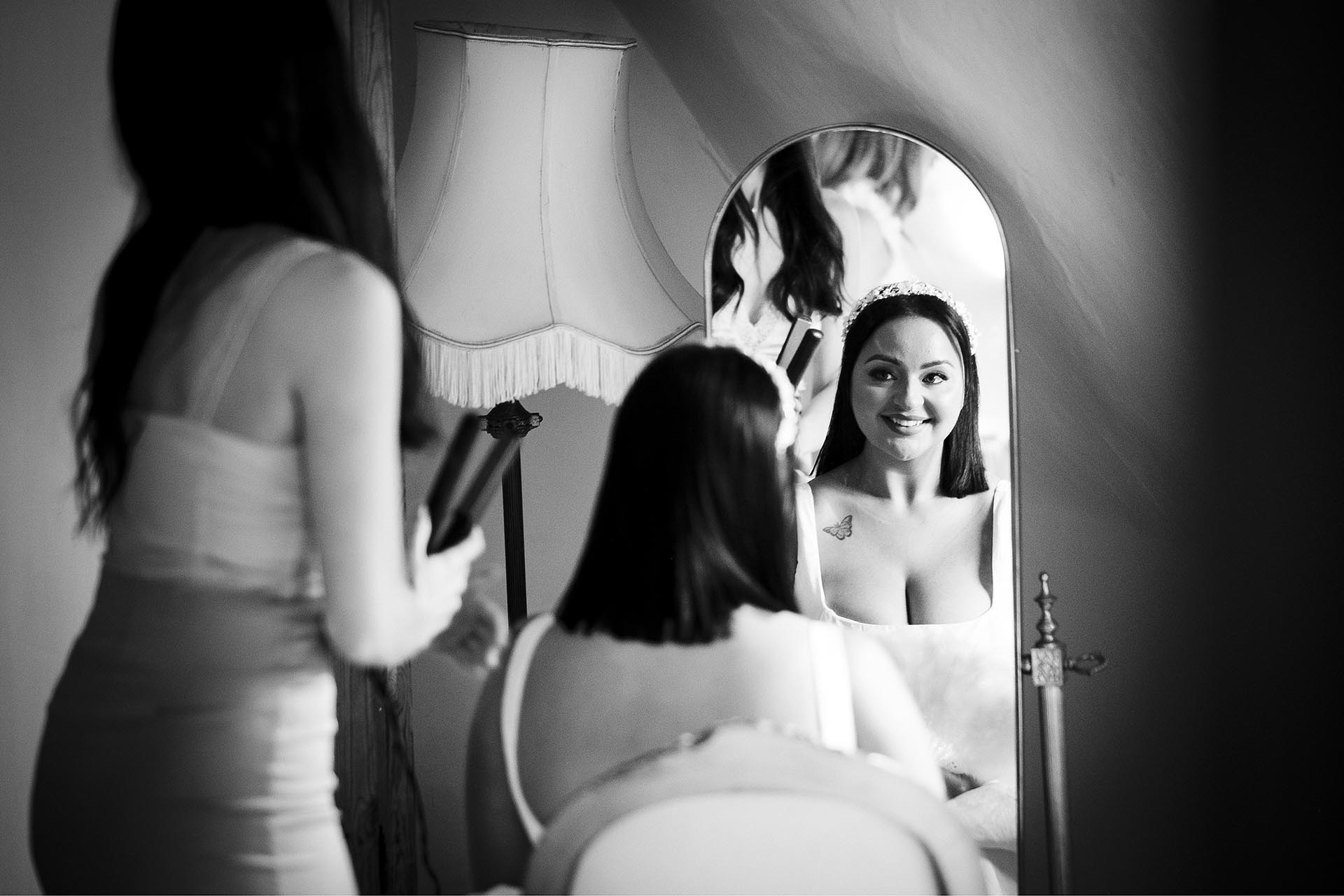 Black and white photograph of bride smiling in a mirror