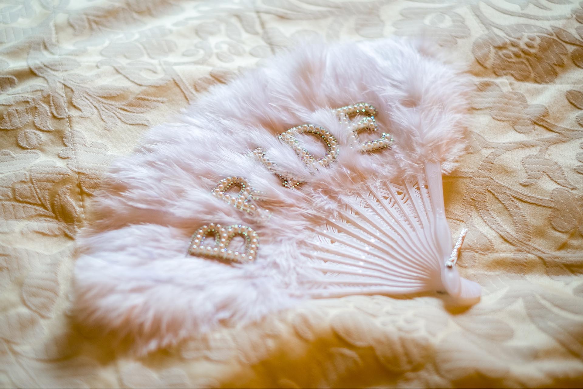 Photograph of white feather fan with letters spelling BRIDE