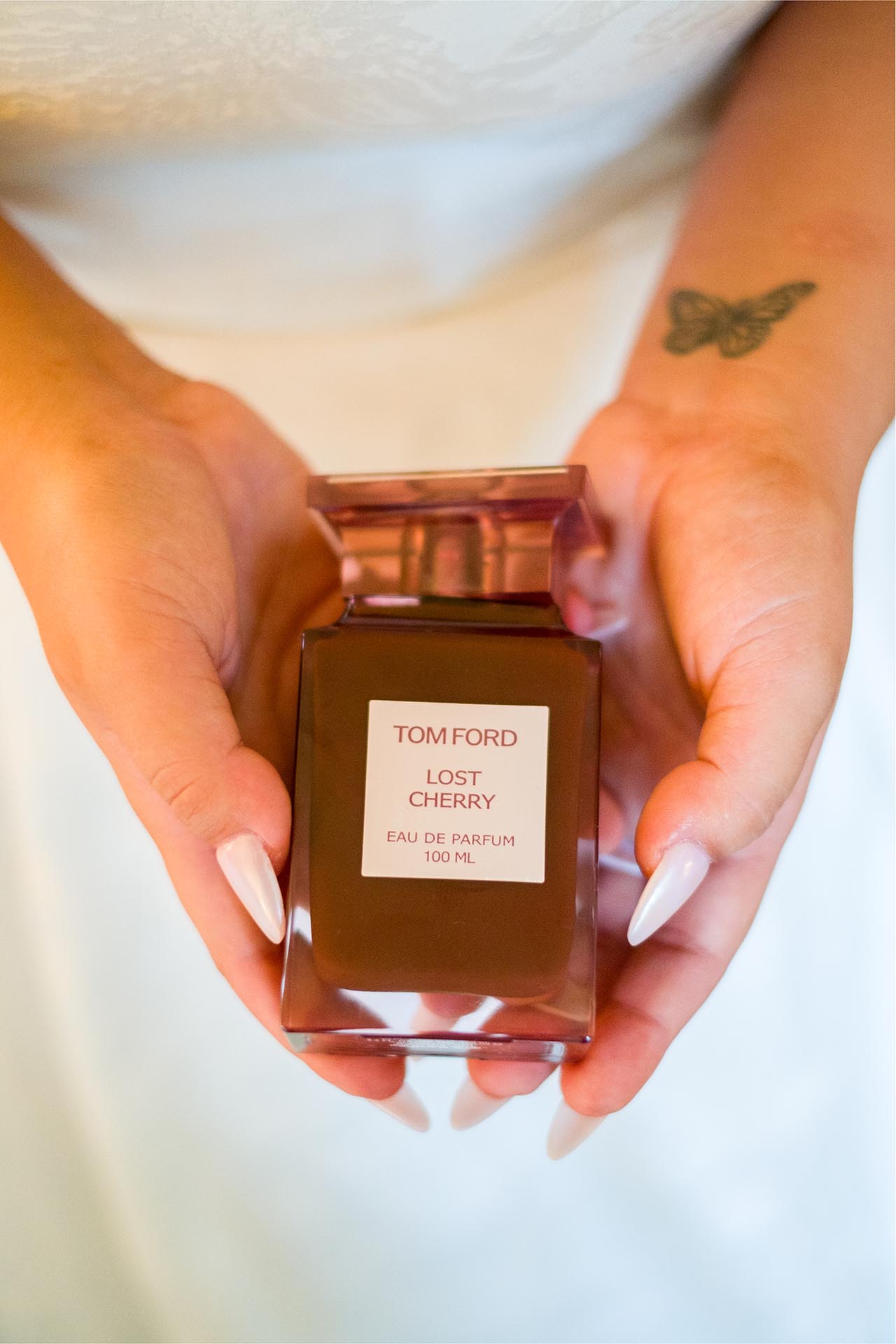 Close-up photograph of bride's hands holding bottle of Tom Ford perfume