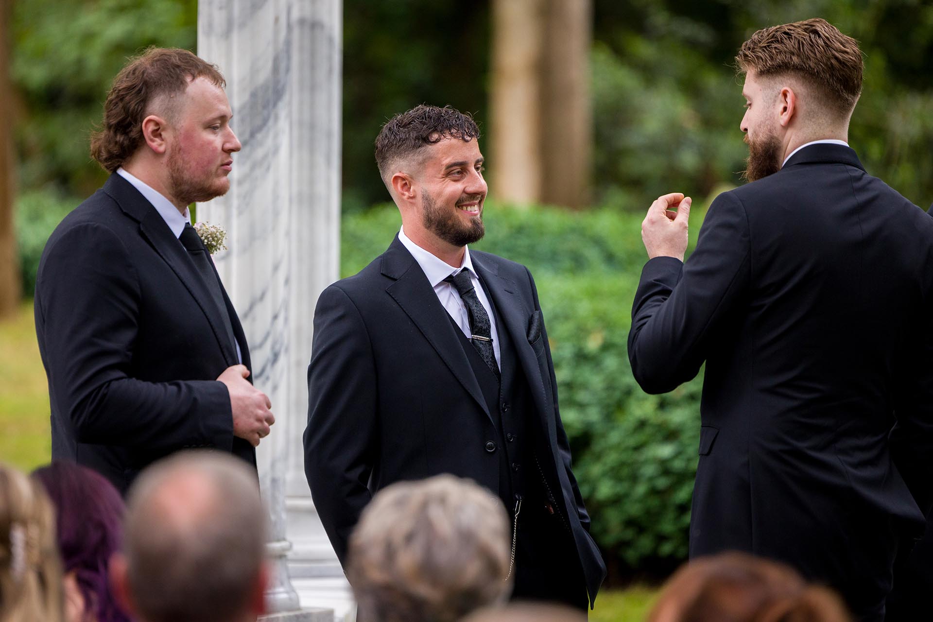 Photograph of groom and groomsmen chatting before outdoor ceremony