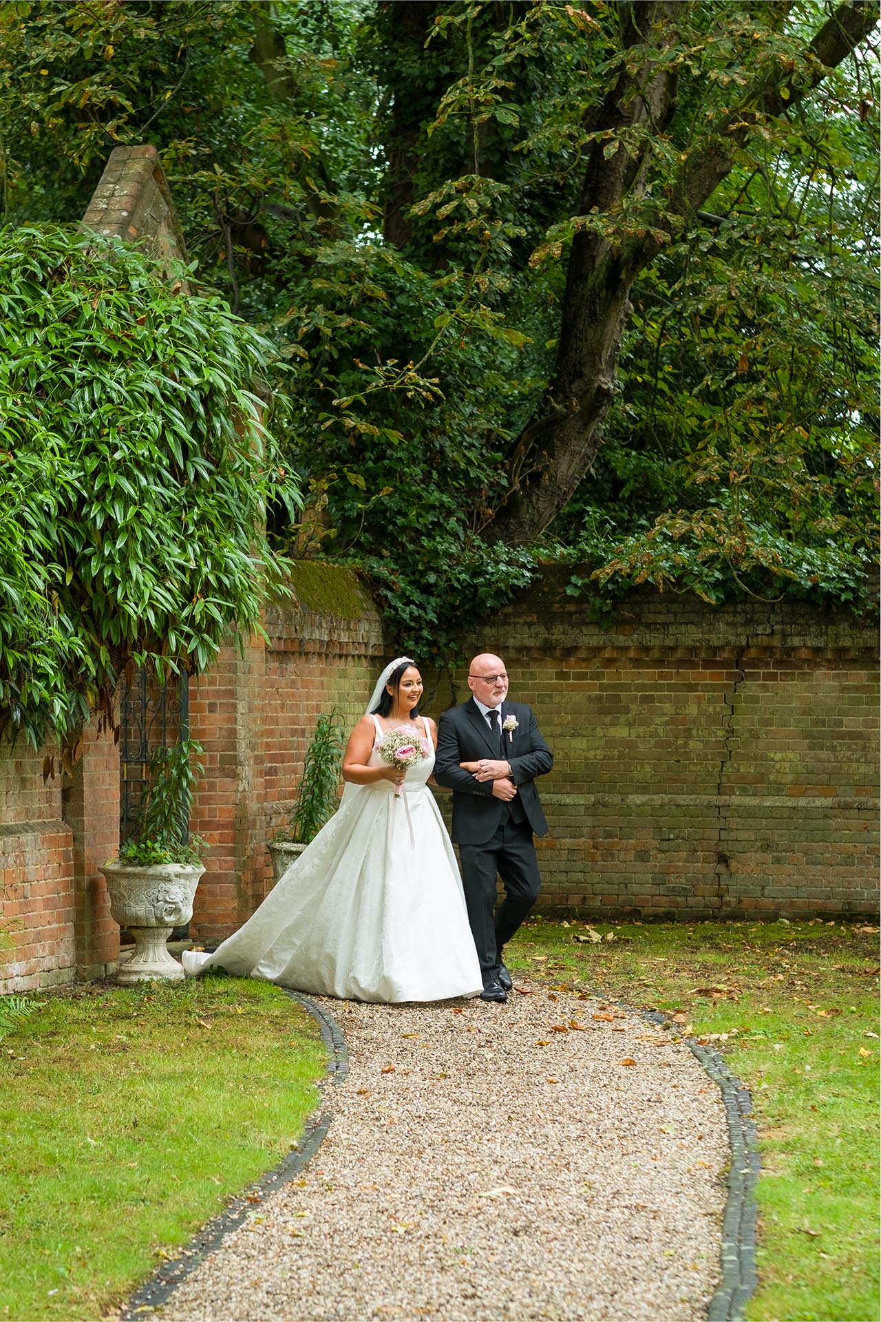Photograph of bride arriving with her father for outdoor ceremony