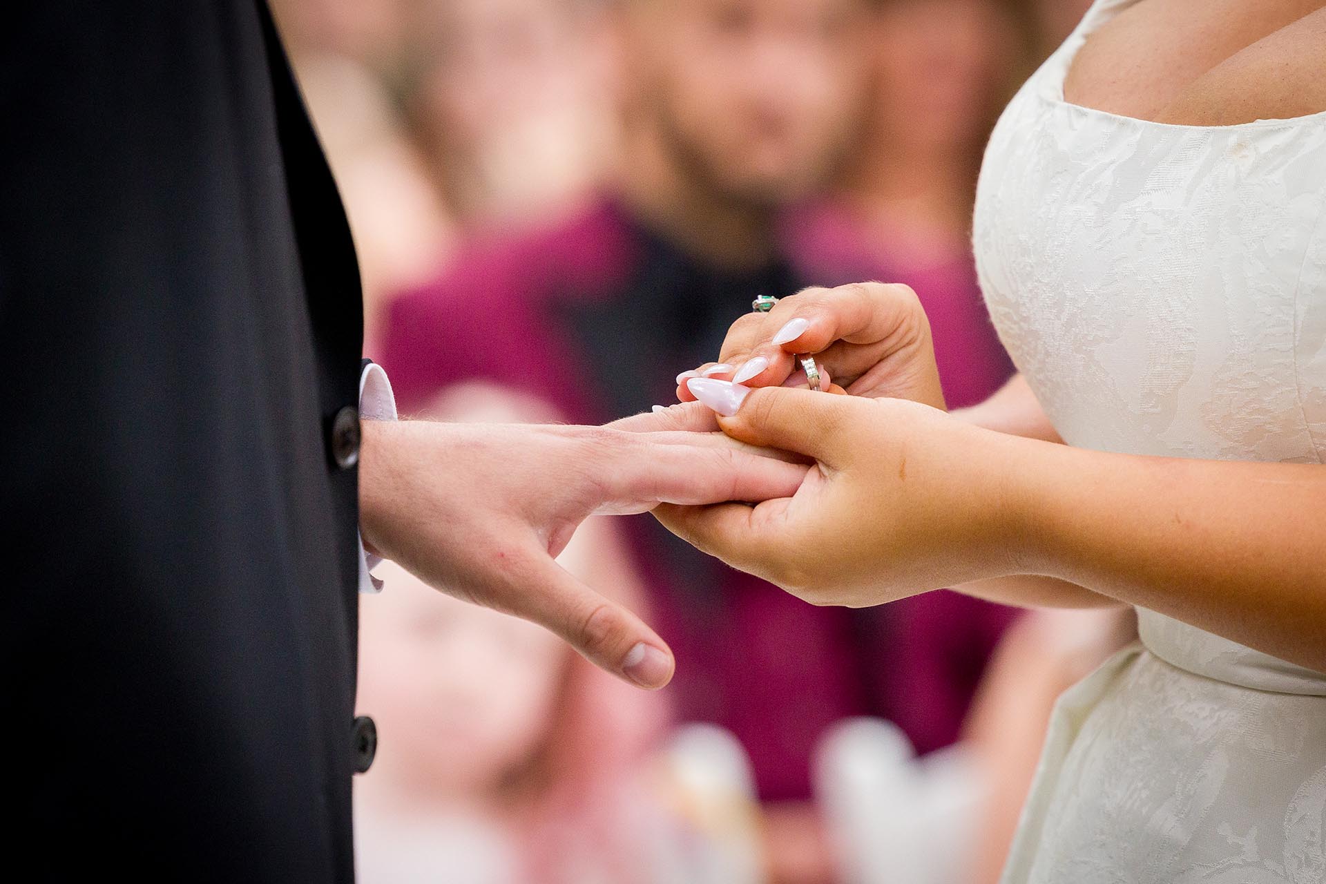 Close-up photograph of bride and groom's hands whilst wedding ring is being put on finger during wedding ceremony