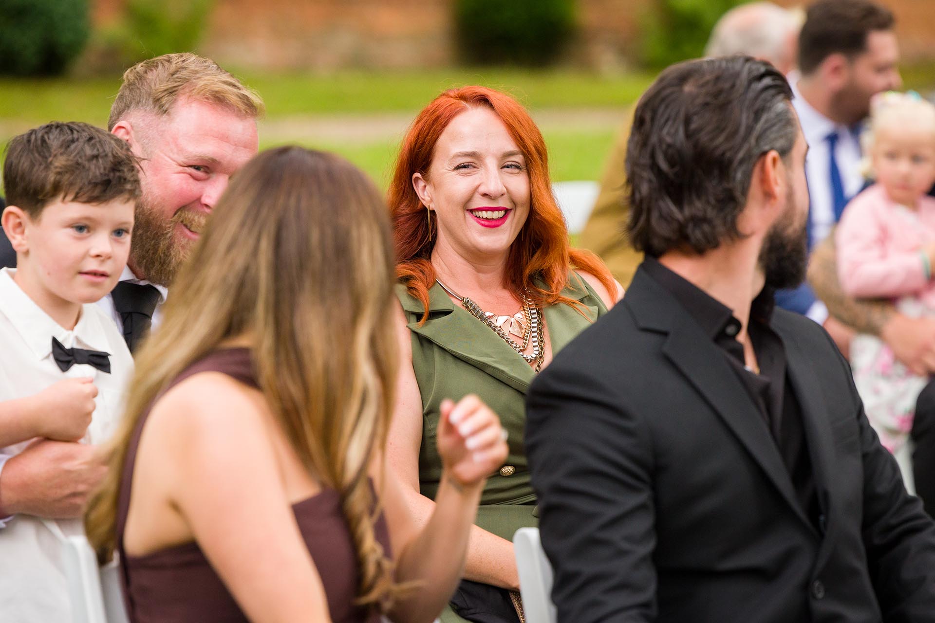 Photograph of wedding guest laughing during outdoor wedding ceremony at Creeksea Place Manor, Burnham-on-Crouch, Essex