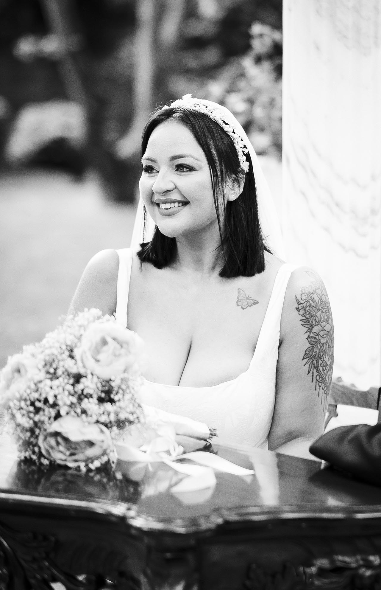 Black and white photograph of bride and groom seated at ceremony table