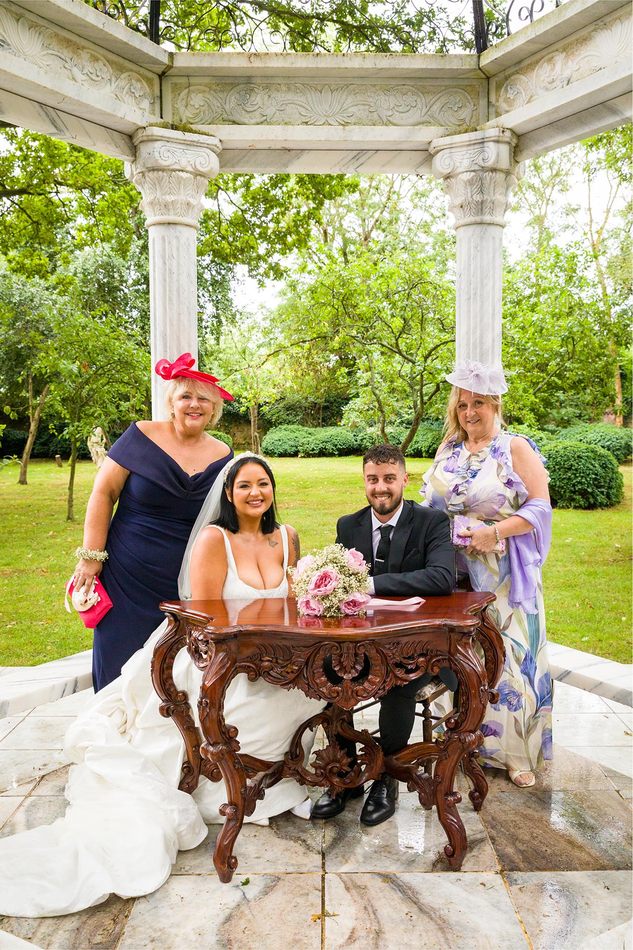 Photograph of bride and groom seated at ceremony table with their mothers at Creeksea Place Manor, Burnham-on-Crouch, Essex