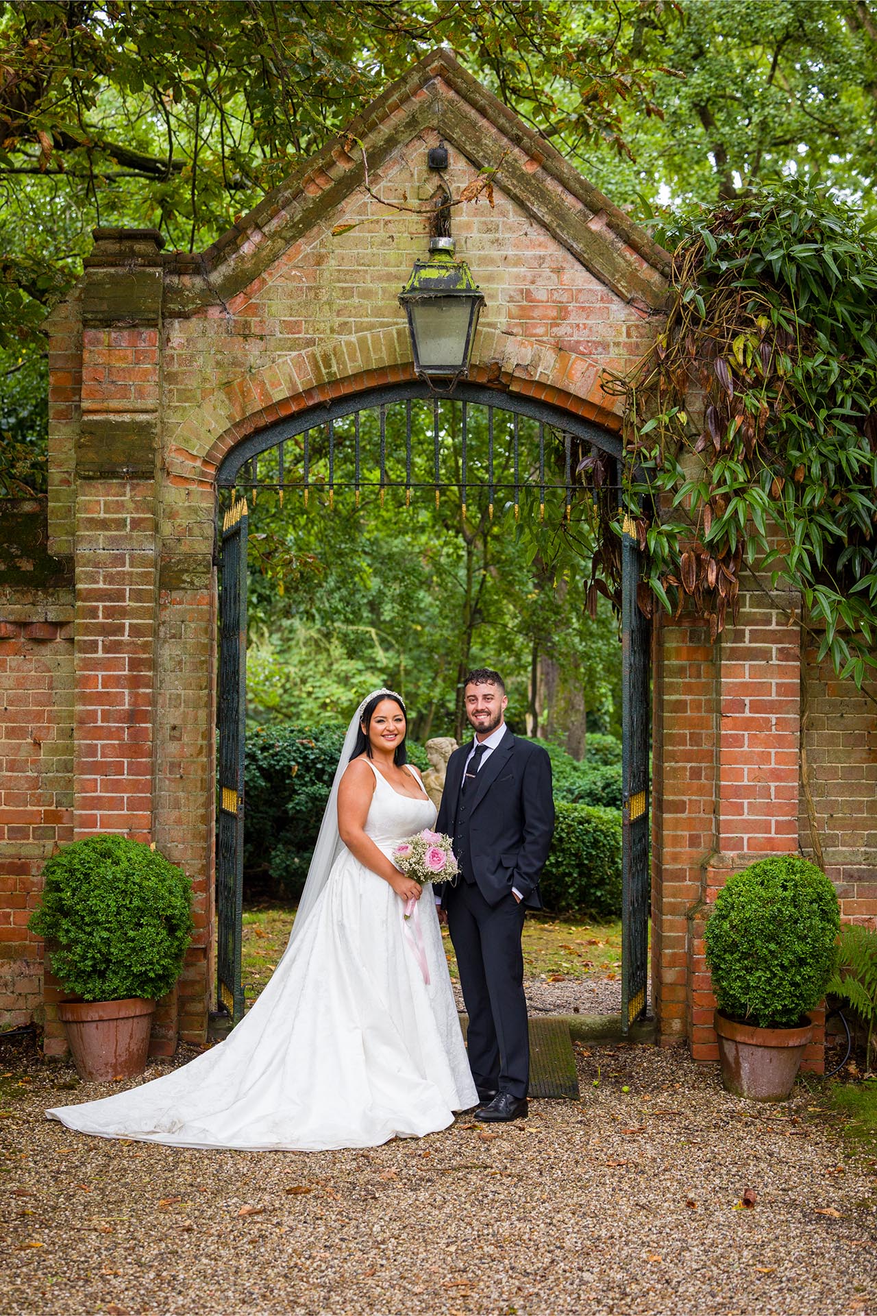 Photograph of bride and groom in front of brick arch at Creeksea Place Manor