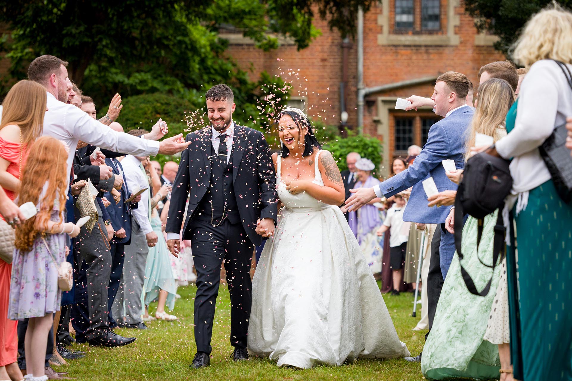 Photograph of guests throwing confetti over bride and groom