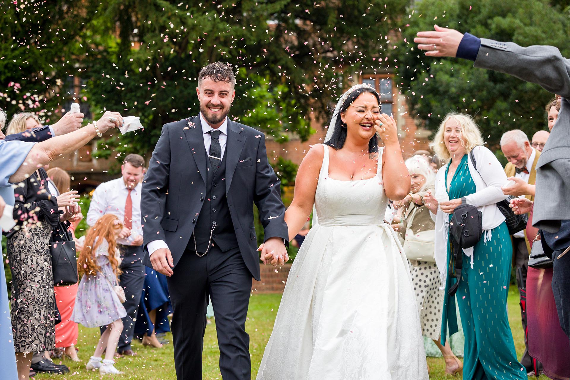Photograph of guests throwing confetti over bride and groom