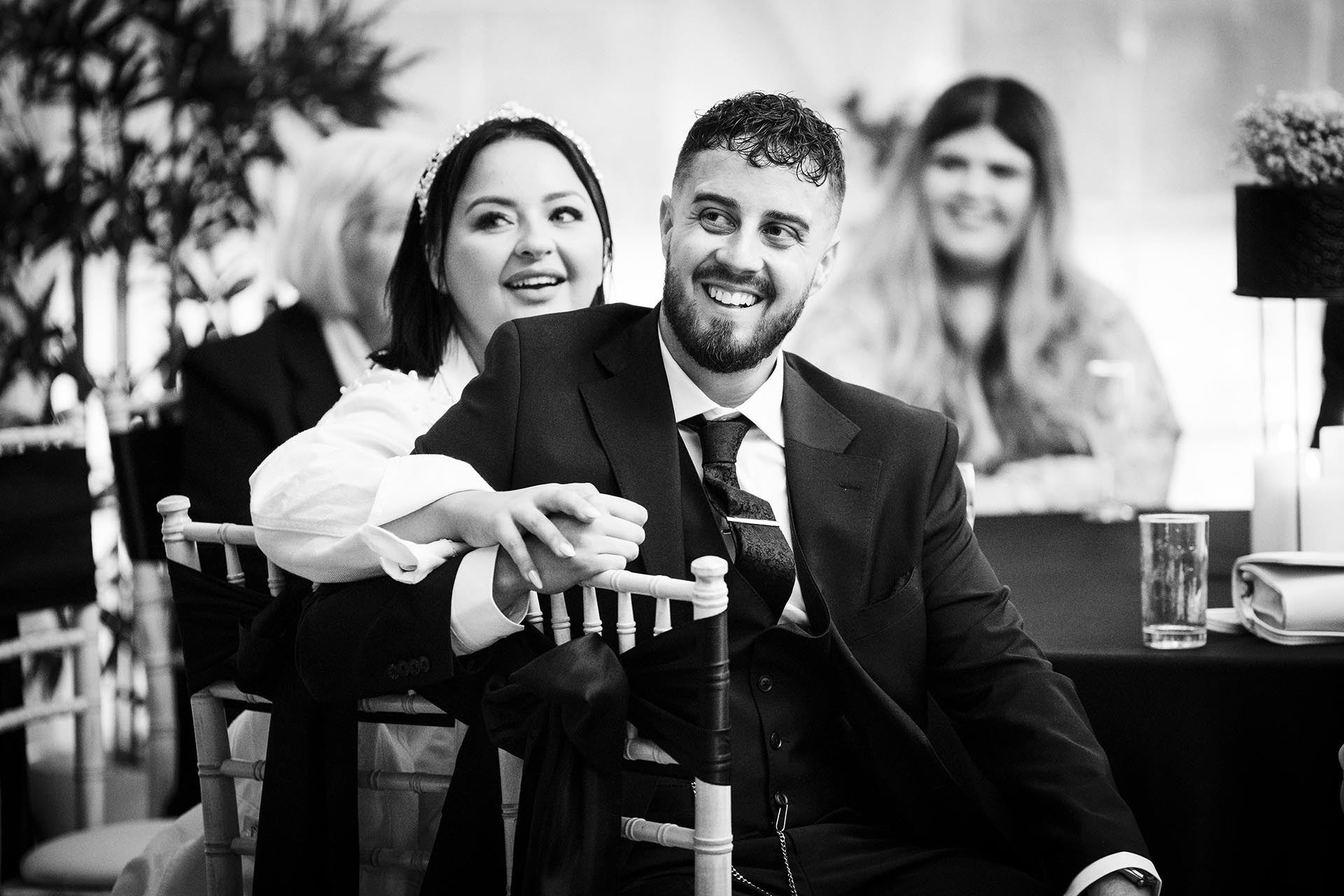 Black and white photograph of bride and groom laughing during speeches
