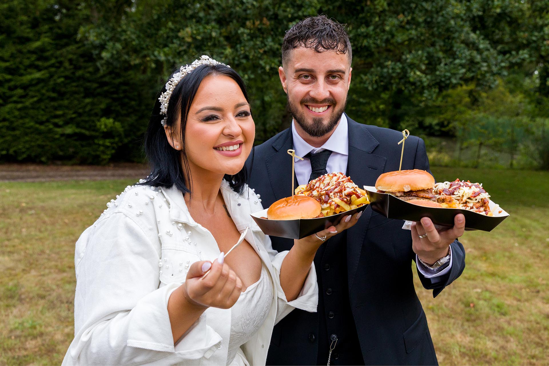 Photograph of bride and groom holding burgers and chips