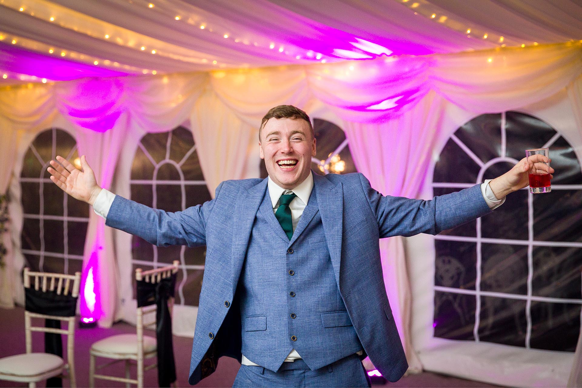 Photograph of laughing wedding guest in a marquee