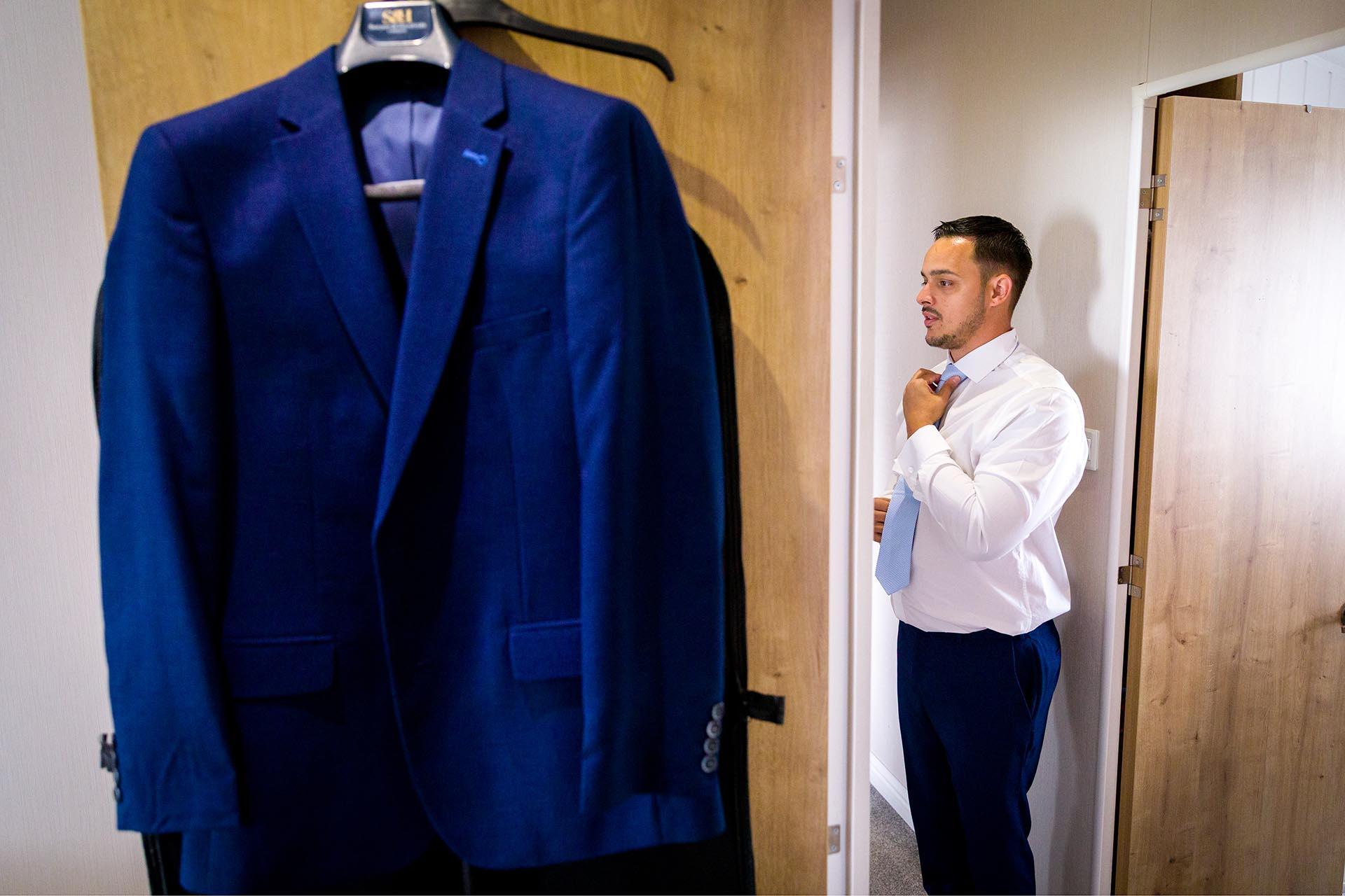 The groom straightening his tie before his wedding ceremony