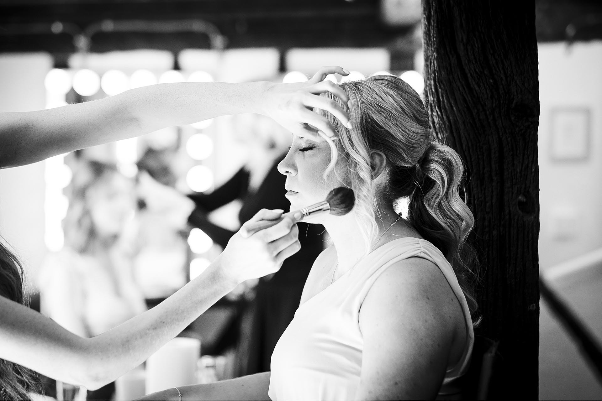 Black and white photograph of make-up being applied to bridesmaid