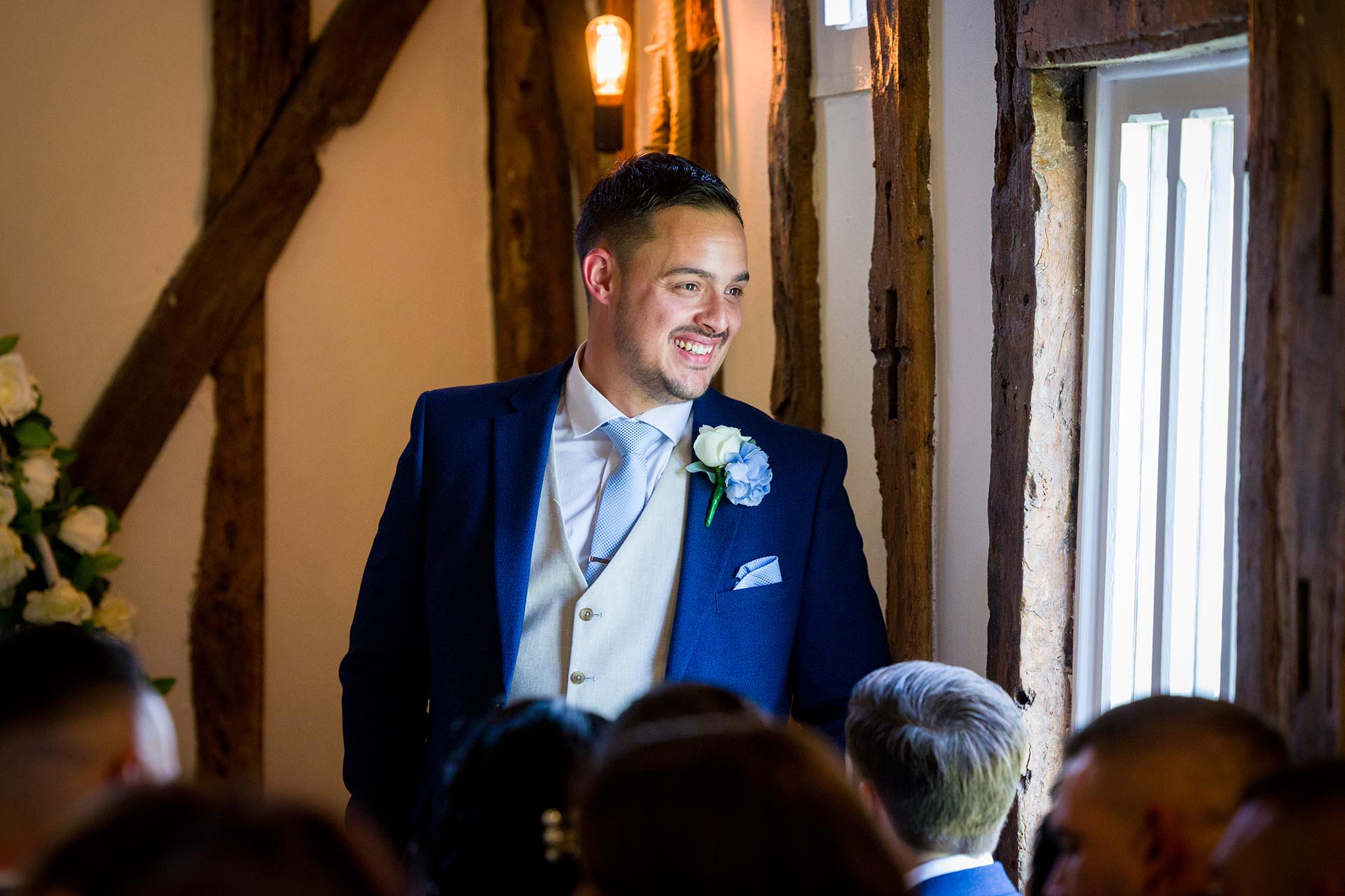 Smiling groom looking out of a window ahead of the wedding cermony