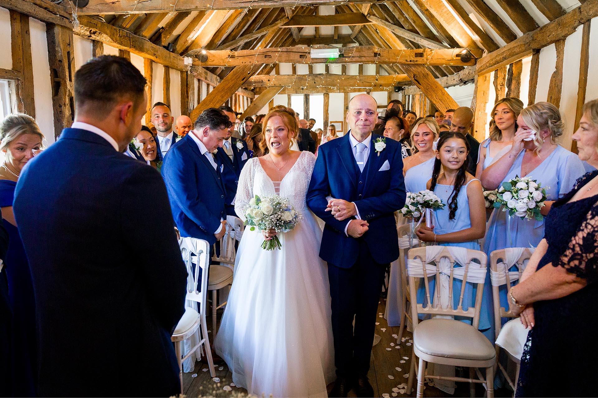 An emaotional bride walking down the aisle with her father