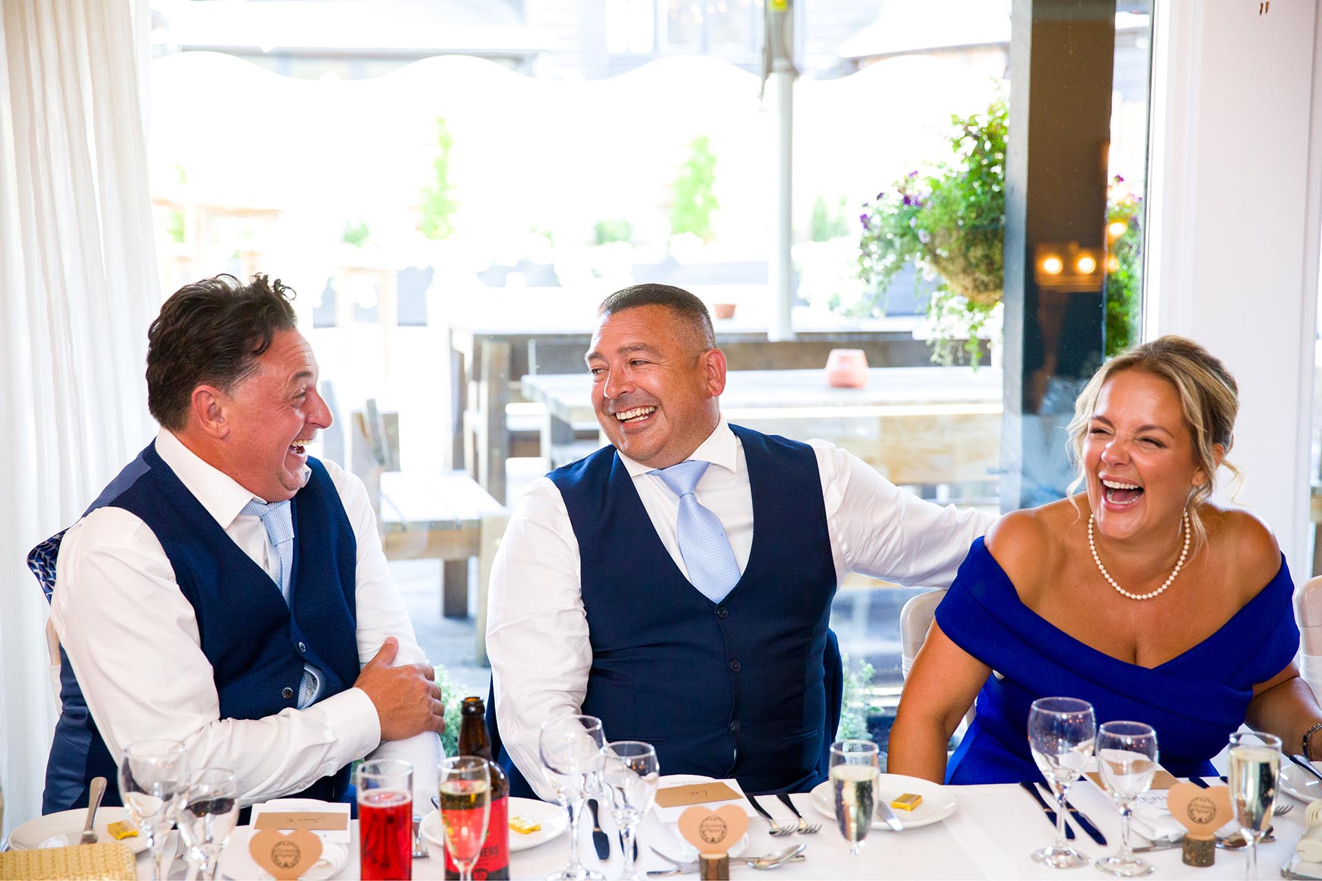 Wedding guests laughing while seated at a dining table