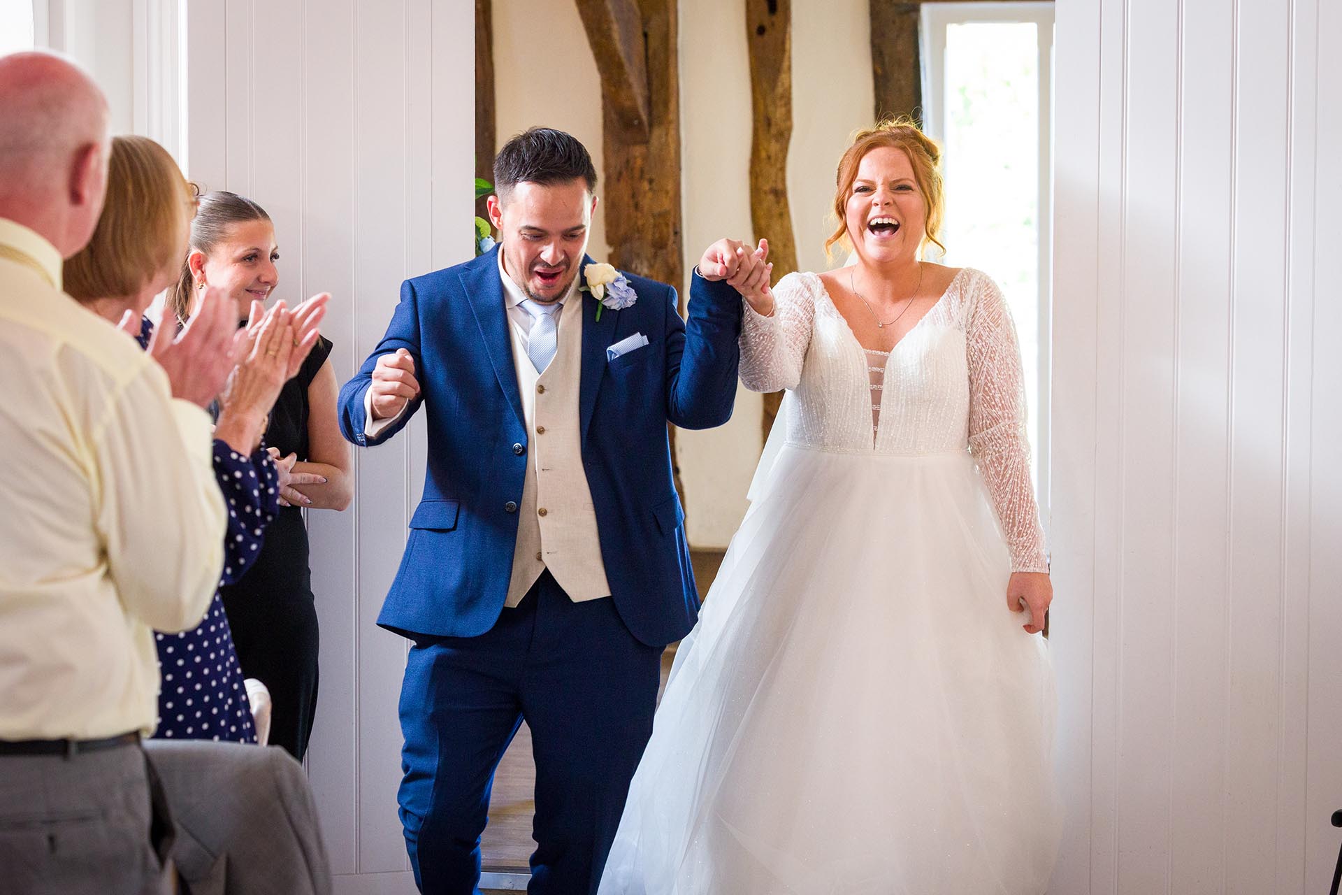Bride and groom laughing and dancing as they enter their wedding breakfast room