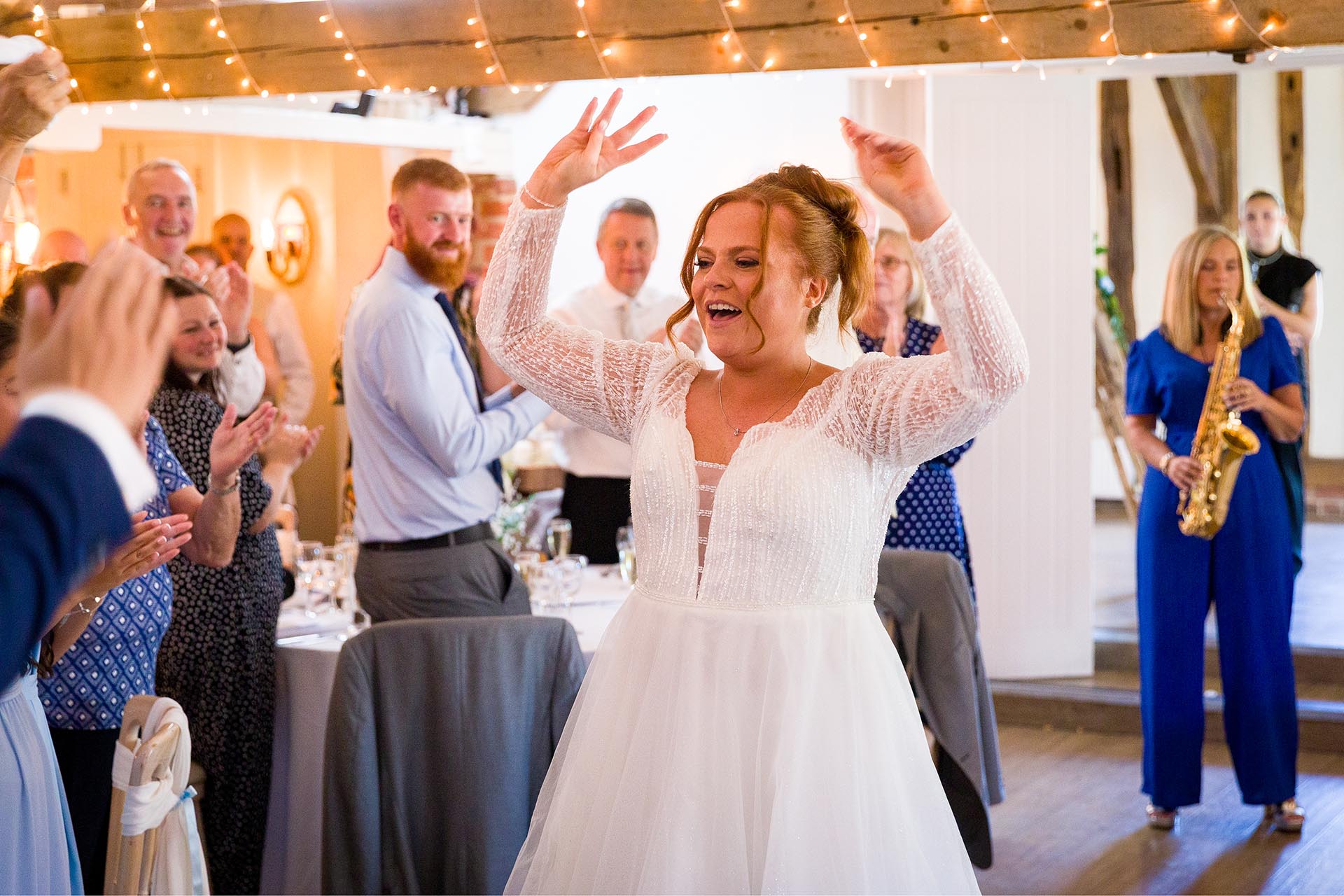 Bride dancing as she entesr the wedding breakfast room with a saxophonist playing in the background