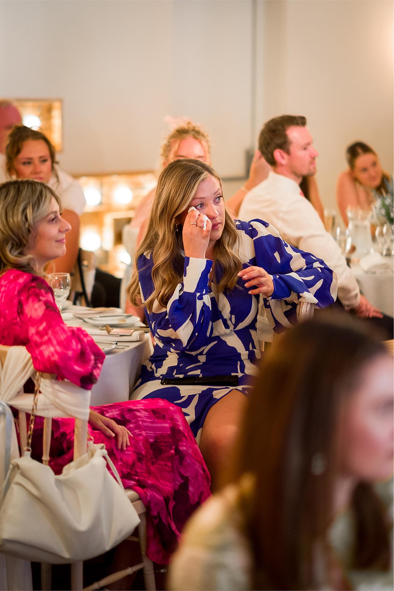 Emotional wedding guest wiping a tear