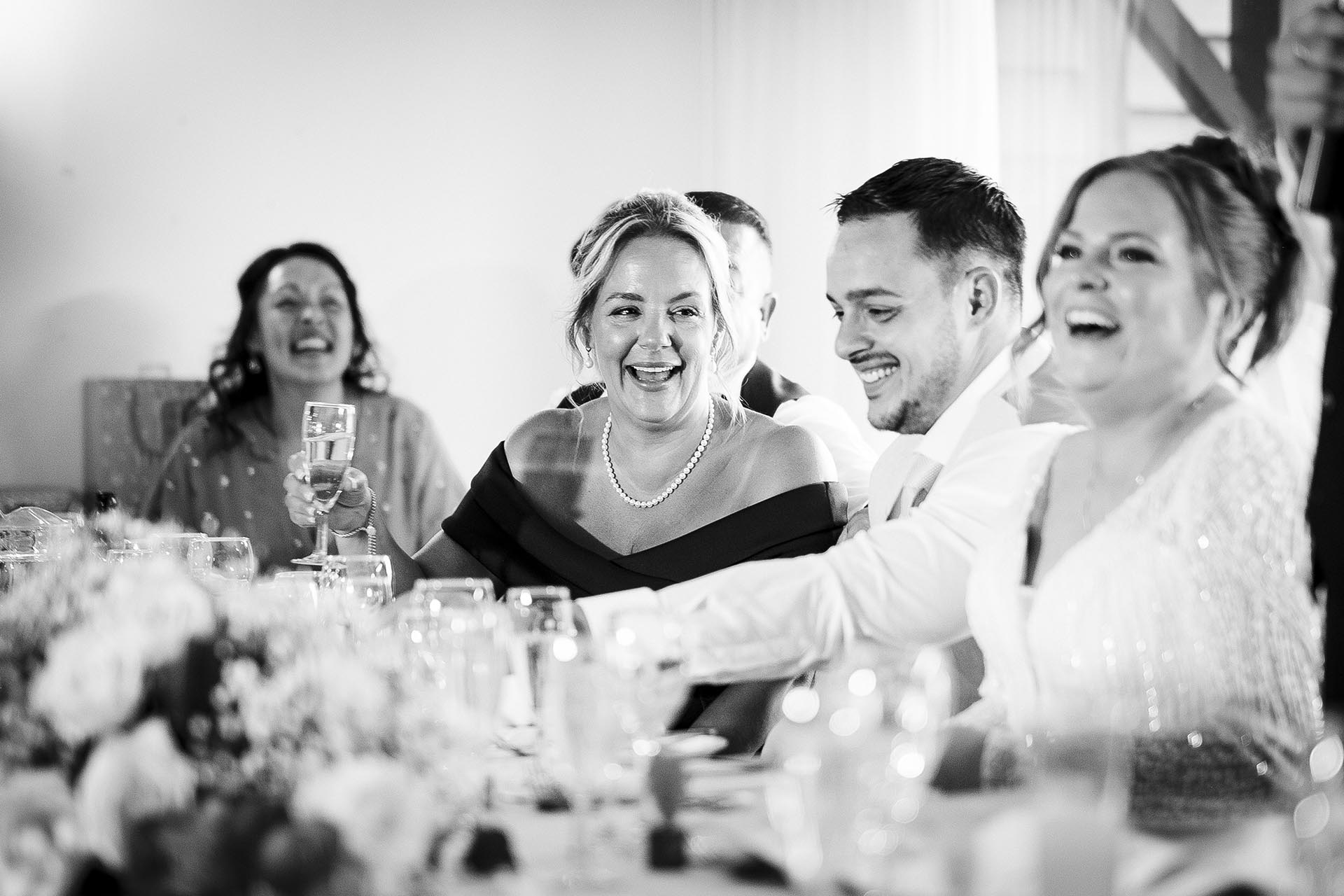 Black and white photograph of wedding guests laughing