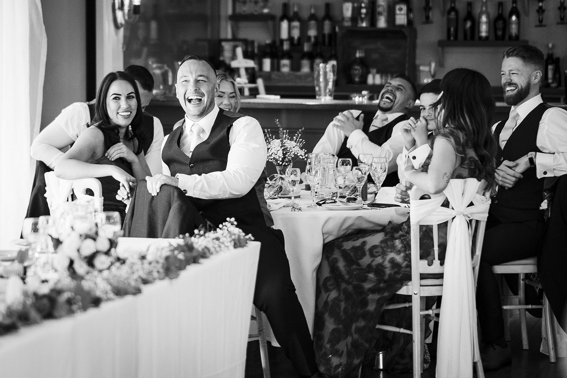 Black and white photograph of wedding guests laughing