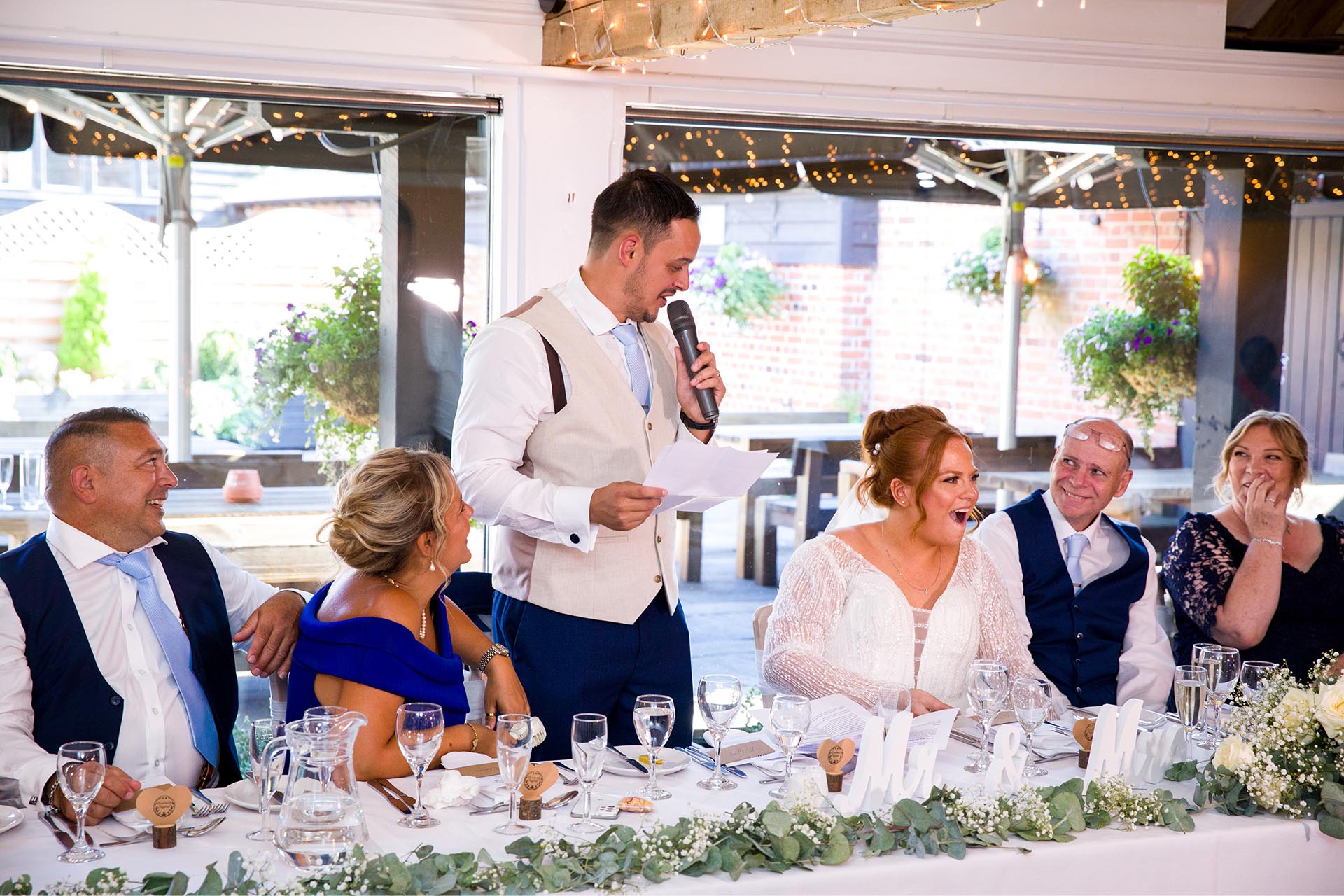 Bride and guests laughing during the groom's speech