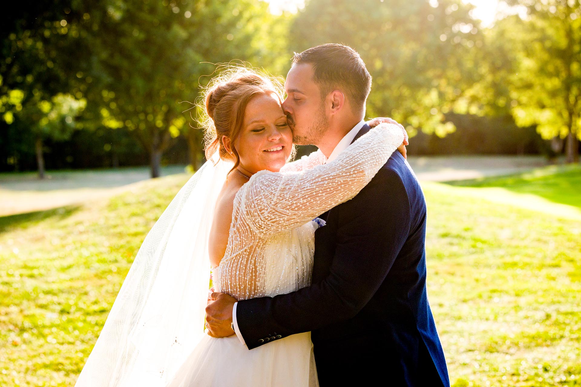 Groom kissing the bride in the late afternoon sun at Little Channels, Essex