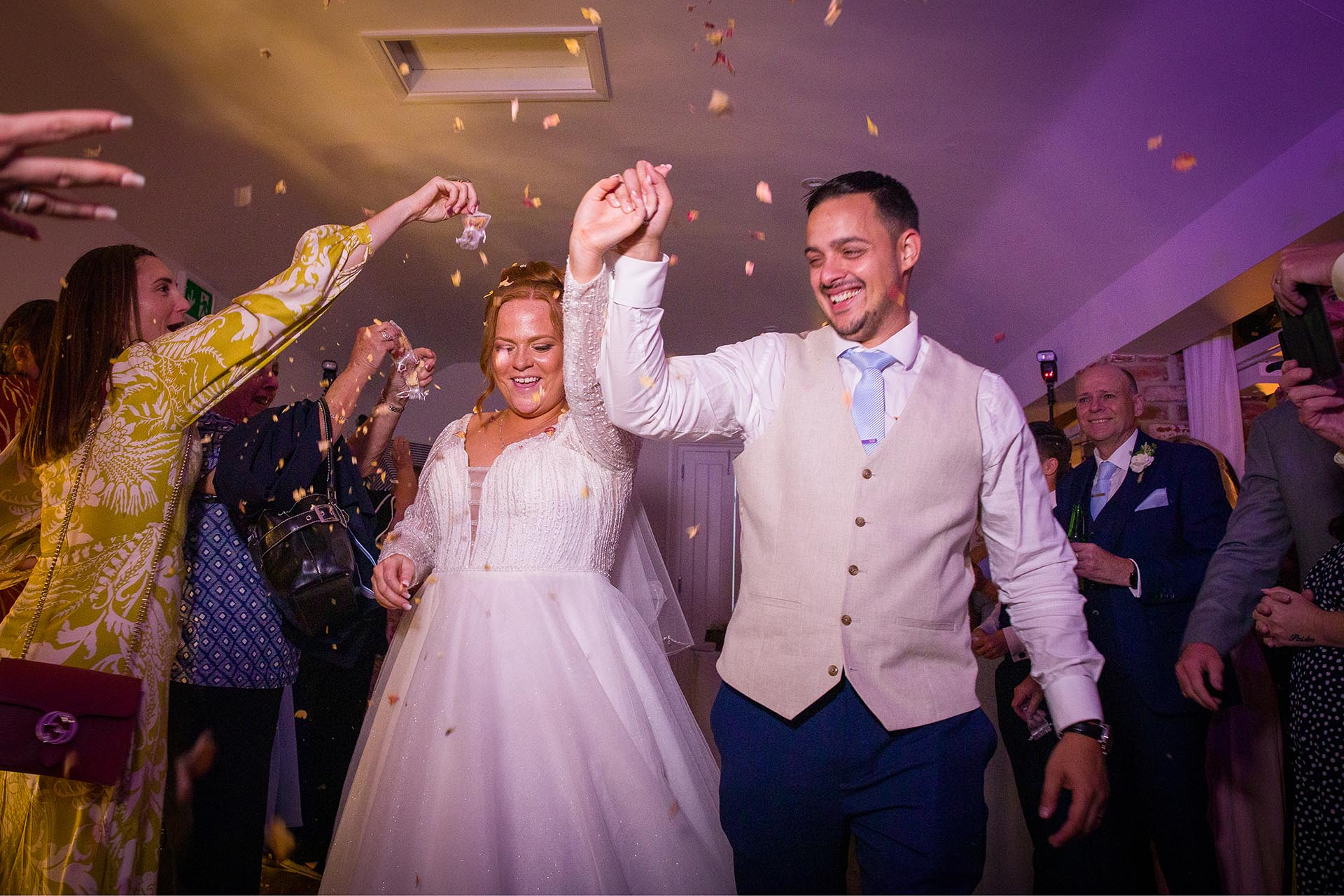 Wedding guests throwing confetti over a smiling bride and groom