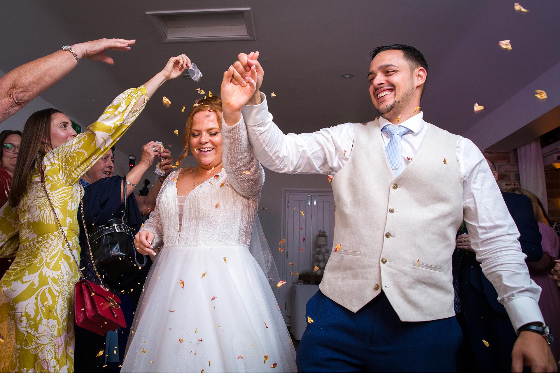 Wedding guests throwing confetti over a smiling bride and groom