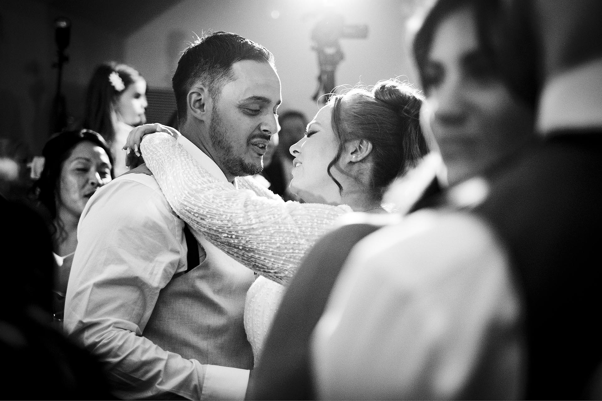 Black and white photograph of bride and groom dancing surrounded by guests