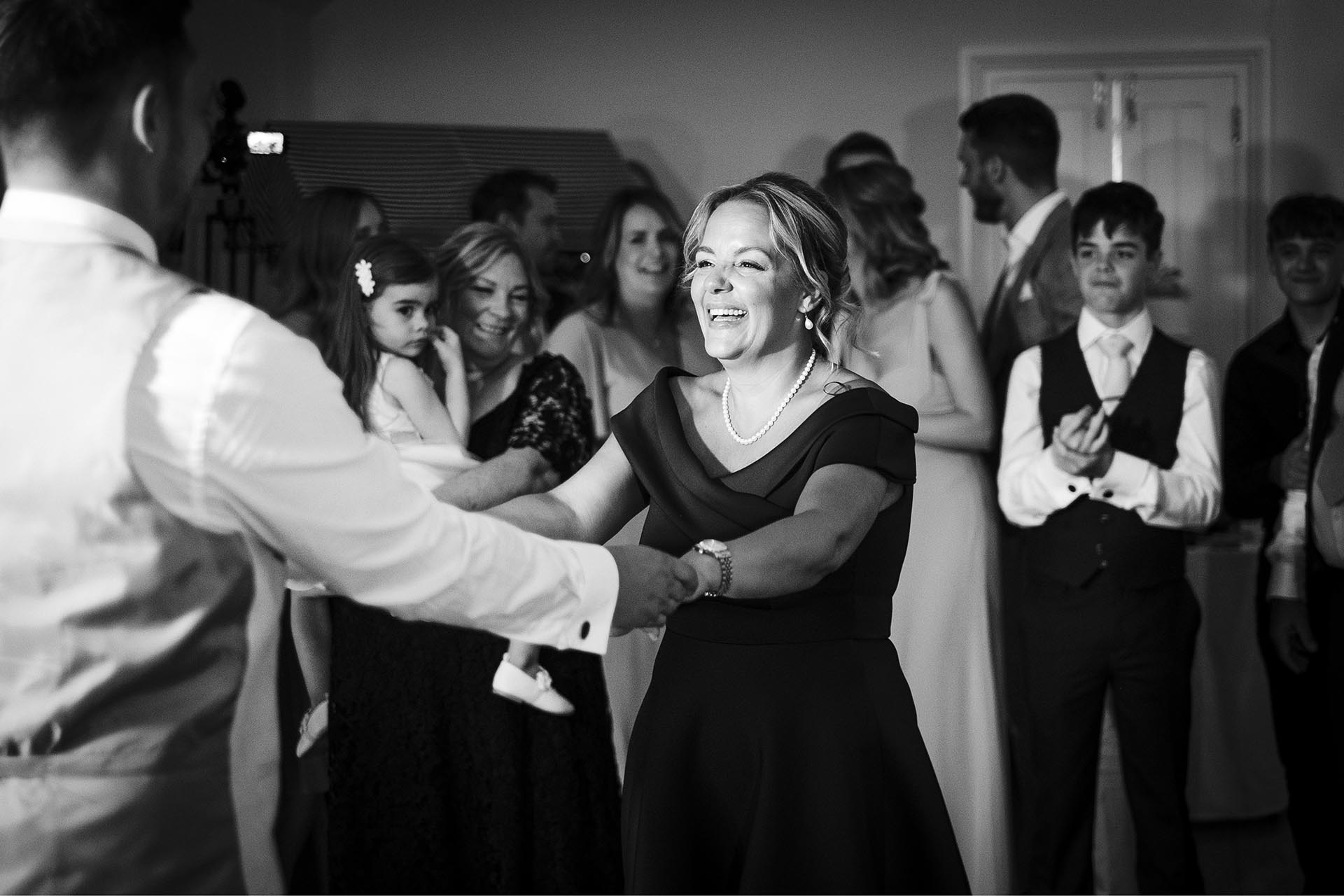 Black and white photograph of the mother of the groom dancing with her son